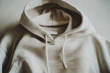 Beige hoodie sweatshirt with hood and drawstrings against a neutral background.