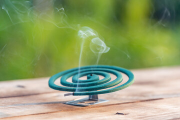 Smoldering mosquito coil in summer garden on wooden table, insect protection