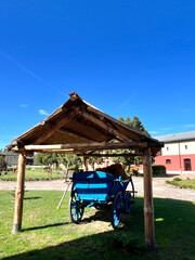 Colorful Wooden Cart Under a Thatched Roof on a Sunny Day