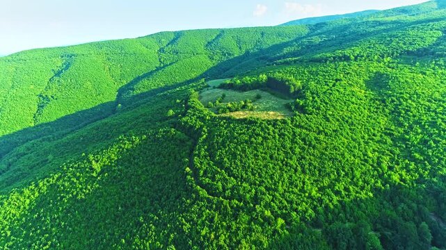 Flight over green mountains slopes