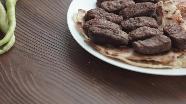 Close-Up of Romanian Mici Sausages Served with Flatbread and Tomatoes on a White Plate
