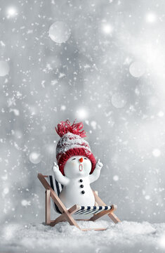 One little snowmen on deck chair in caps on snow in the winter. Background with a funny snowman. Christmas card.
