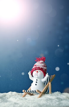 One little snowmen on deck chair in caps on snow in the winter. Background with a funny snowman. Christmas card.