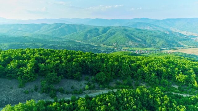 Flyover, deciduous forest, mountains slopes, beautiful village in the valley