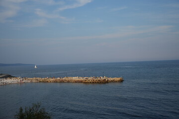 Stone breakwater in calm sea near Nessebar, Bulgaria. Blue water and sky creating peaceful coastal landscape with minimal composition.