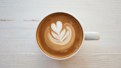 Top view of a cup of coffee with beautiful latte art in the foam, placed on a light wooden table. Perfect for themes related to coffee culture, morning routines and lifestyle.