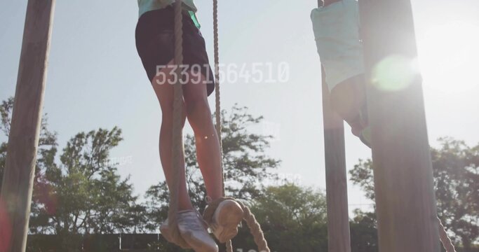 Climbing boy wearing shirt and shorts gripping thick ropes on wooden posts at outdoor playground