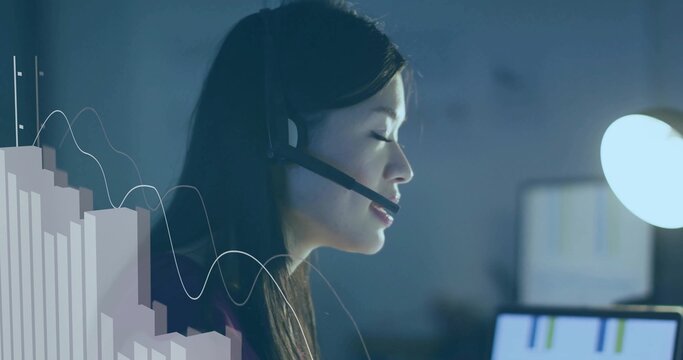 Analyzing charts adult Chinese woman wearing headset at office desk, with glowing monitor overlay