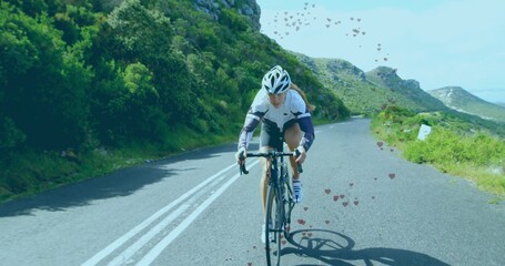 Obraz premium Riding solo female cyclist pedaling uphill on mountain road, with aerodynamic helmet and road bike