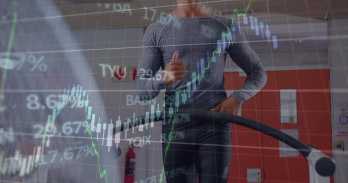 Running male wearing grey top and black pants on treadmill at gym, displaying financial chart