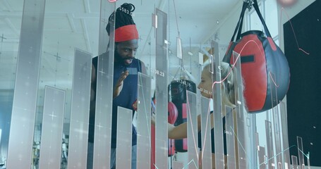 Trainee practicing boxing with coach in boxing gym, showing heavy bags, gloves, wraps, data overlay