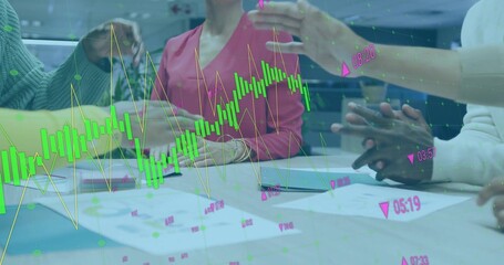 Professionals collaborating in conference room, reviewing printed charts and digital graph overlay