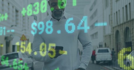 Holding smartphone, man wearing grey sweater standing on urban street, with holographic market data