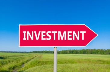 Investment symbol. Concept word Investment on beautiful red road sign. Beautiful blue sky green grass and forest peaceful nature background. Business investment concept. Copy space.