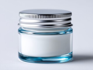 A glass jar with a silver lid on a white surface