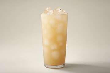 A tall glass filled with a light, beige-colored beverage, topped with ice cubes, sits against a plain backdrop.