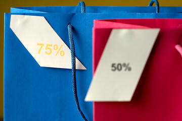 Two shopping bags with 75% and 50% written on them. The bags are blue and pink. Sale