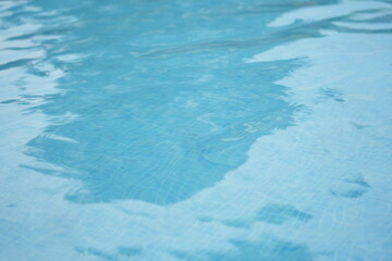 Obraz premium Blue swimming pool water with sunlight reflections near tiled edge. Clear aquatic texture — summer background symbolizing freshness, relaxation, travel, and resort lifestyle.
