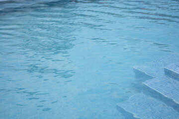 Clear blue swimming pool water with soft sunlight reflections. Minimal aquatic background — concept of freshness, purity, relaxation, and summer vacation.