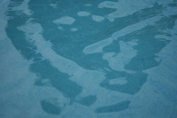 Obraz premium Blue swimming pool water surface with gentle ripples and sunlight reflections. Calm aqua texture creating a refreshing and relaxing summer atmosphere. Perfect background for vacation, spa, and wellnes
