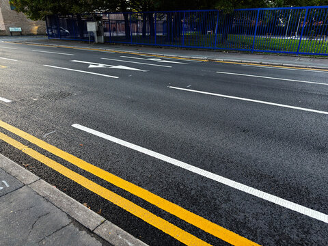 Manchester street scene with double yellow lines white road markings and a blue fence