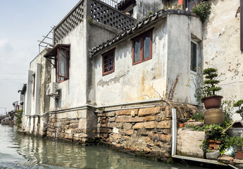 Traditional houses with tiled roofs on a narrow canal in an ancient Chinese water town. Suzhou, China,