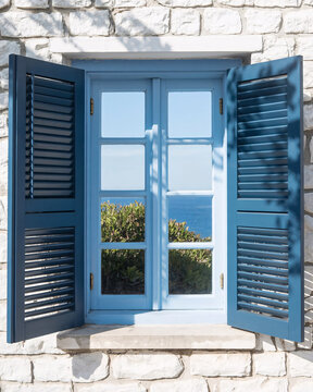 Open blue window with sea view and stone wall, ideal for vacation and travel theme