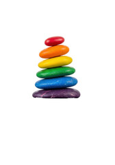 Rainbow-colored, smooth river pebbles stacked in a delicate cairn, reflecting on calm water, against a white studio background with copy space, concept of perfect balance and harmony