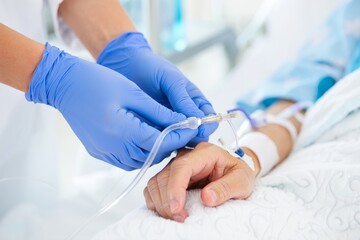 Close-up of a nurse's hands in blue gloves adjusting an intravenous therapy IV drip for a patient in a hospital bed