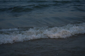 Calm sea waves washing the sandy beach at sunset. Natural seascape with gentle surf and horizon view — peaceful ocean background symbolizing travel, relaxation, and summer nature.