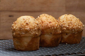 Three cupcakes on cooling wire rack, Three freshly baked cupcakes in a row on wire cooling rack.