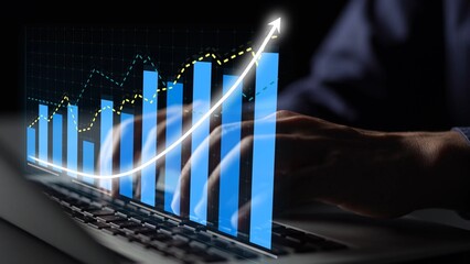 A close-up view of hands typing on a laptop, with a digital graph overlay illustrating growth trends in data analytics and business performance measures. Copula