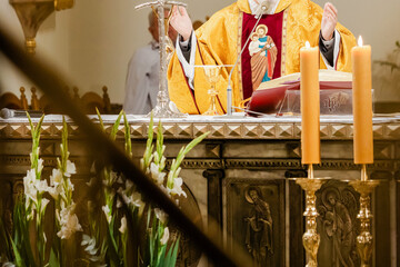 Catholic priest celebrating Holy Mass during liturgy with chalice, Bible, and liturgical vestments inside church, Eucharist and communion ceremony in Christian tradition