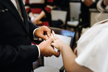 Bride and groom exchanging wedding rings during church ceremony, close-up of hands with rings...