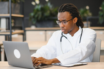 Young african american doctor working on laptop in modern clinic