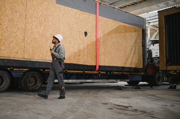 Construction worker supervising prefabricated house transportation in factory