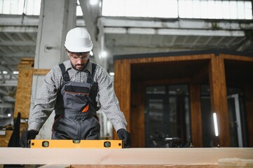 Obraz premium Arab carpenter using spirit level on wooden plank in workshop