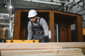 Arab carpenter using spirit level on wooden plank for modular house production