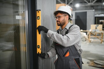 Construction worker using spirit level while installing modular house door