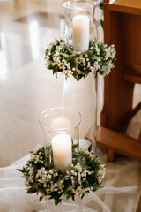 Romantic wedding church decoration with burning candles in glass holders and floral arrangements, warm light creating peaceful atmosphere for ceremony and celebration