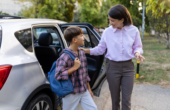 Mom helping son out of car to go school