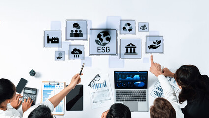 A business team engages in collaboration over ESG strategies using digital tools and data visualization, aiming for sustainable practices and effective governance. Trope