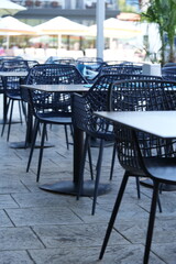 Outdoor hotel terrace with modern blue mesh plastic chairs and white dining tables – empty restaurant patio furniture close up on stone floor, stylish hospitality design and contemporary travel concep