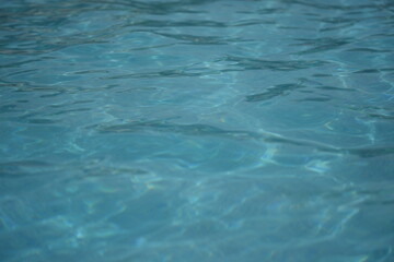 Clear blue water surface in a swimming pool with gentle ripples and reflections. Calm and refreshing texture, perfect for summer, wellness, and travel themes.