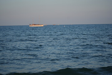 Small passenger or excursion boat sailing on calm blue sea under clear sky. Peaceful seascape with horizon — perfect for travel, vacation, and marine themes