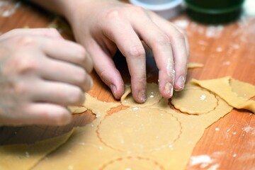 Child's hand picking up a piece of raw honey cookie dough for baking