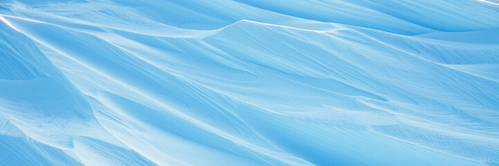 Snow texture. Wind sculpted patterns on snow surface. Wind in the tundra and in the mountains on the surface of the snow sculpts patterns and ridges. Arctic, Polar region. Winter panoramic background.