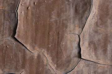 Brown peeling paint on the wall. Old concrete wall with cracked flaking paint. Weathered rough painted surface with patterns of cracks and peeling. High resolution texture for background and design.