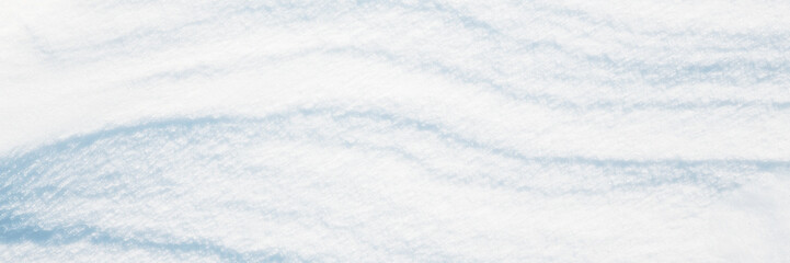 Wide panoramic winter background with snowy ground. Natural snow texture. Wind sculpted patterns on snow surface.