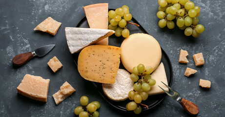 Different types of cheese with grapes on blue background